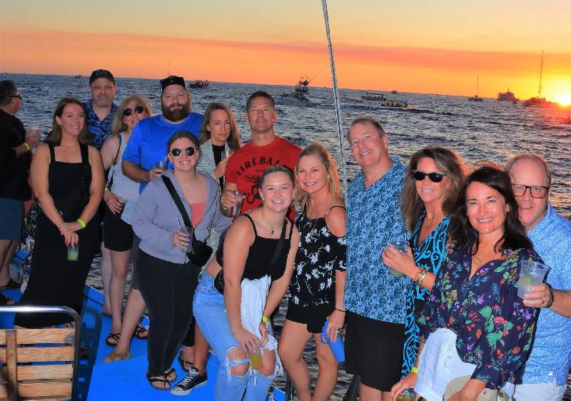 Group celebrating on catamaran at sunset Cabo San Lucas
